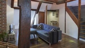 Un loft moderne avec des poutres apparentes en bois, un canapé gris et un escalier.