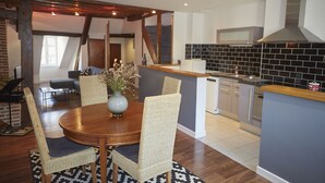 Une cuisine moderne avec un coin repas, comprenant une table en bois, des chaises en osier et un vase rempli de fleurs.