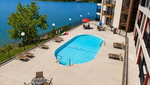 Une piscine dotée de chaises longues et de parasols, avec vue sur un lac.