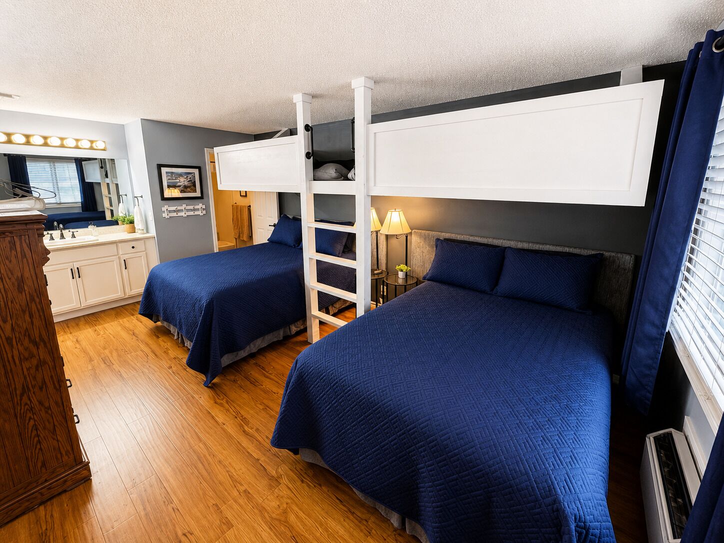 A bedroom with bunk beds, a vanity with a mirror, and a window with blinds.