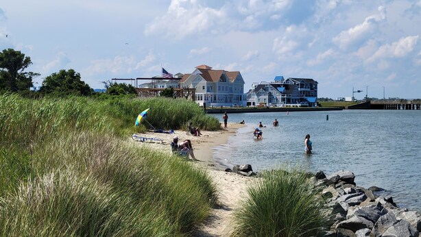 A beach with a row of houses in the background, a sandy path, and people enjoying the water. - 🏖️AMAZING 4 Bd, West Ocean City 🏖️ (Ocean City)