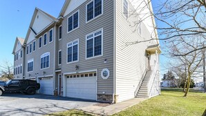 A two-story residential building with a garage, a staircase leading to the second floor, and a well-maintained lawn. - 🏖️AMAZING 4 Bd, West Ocean City 🏖️ (Ocean City)
