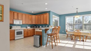 A kitchen with wooden cabinets, a stove, a microwave, and a sink. There are two wooden chairs and a table. - 🏖️AMAZING 4 Bd, West Ocean City 🏖️ (Ocean City)