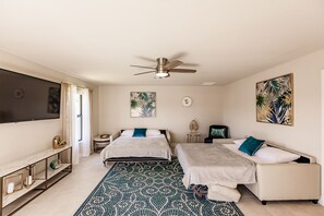 Two single beds with matching headboards and footboards, a large flat-screen TV, and a console table with a globe and candle holder.