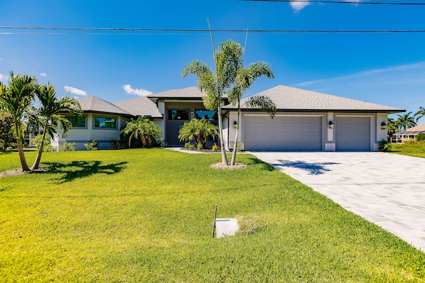 Stunning two-story home with a garage, lush lawn, and palm trees, set amidst a beautifully maintained landscape.