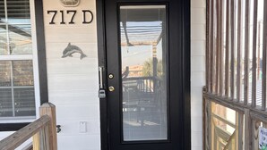 Eine schwarze Tür mit Fensterteil, ein hölzernes Briefkasten und eine Delfin-Dekoration an der Wand.
