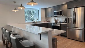 A modern kitchen with a central island, stainless steel appliances, and pendant lighting.