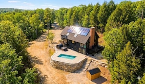Ett hus med en swimmingpool, solpaneler och en terrass i sten.