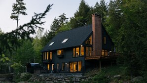 A modern house with a stone foundation, large windows, and a wooden deck.
