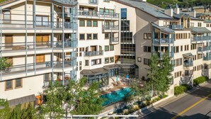 Un hotel de varios pisos con balcones, piscina y jardín ajardinado.