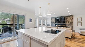 Una cocina moderna con una isla grande, un área de comedor con un sofá y una chimenea.