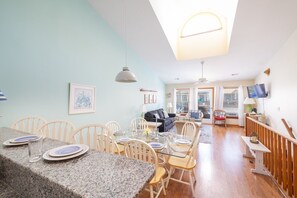 A dining area with a granite table, white chairs, and a ceiling light fixture.