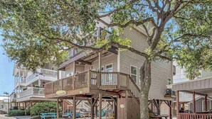 A wooden building with a balcony and a tree in front.
