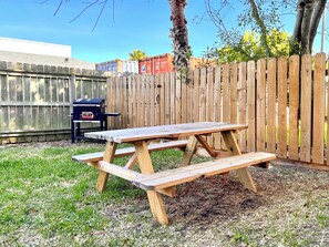 A wooden picnic table with benches in a backyard.