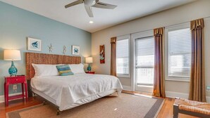 A bedroom with a bed, two nightstands, a ceiling fan, and a large window with curtains. - 🌈Amzng Gulf view, 4 Bd/3.5 Bath Home,🏖Pvt Heated Pool☀️,🌴Just Steps to Gulf🌴 (Panama City Beach)