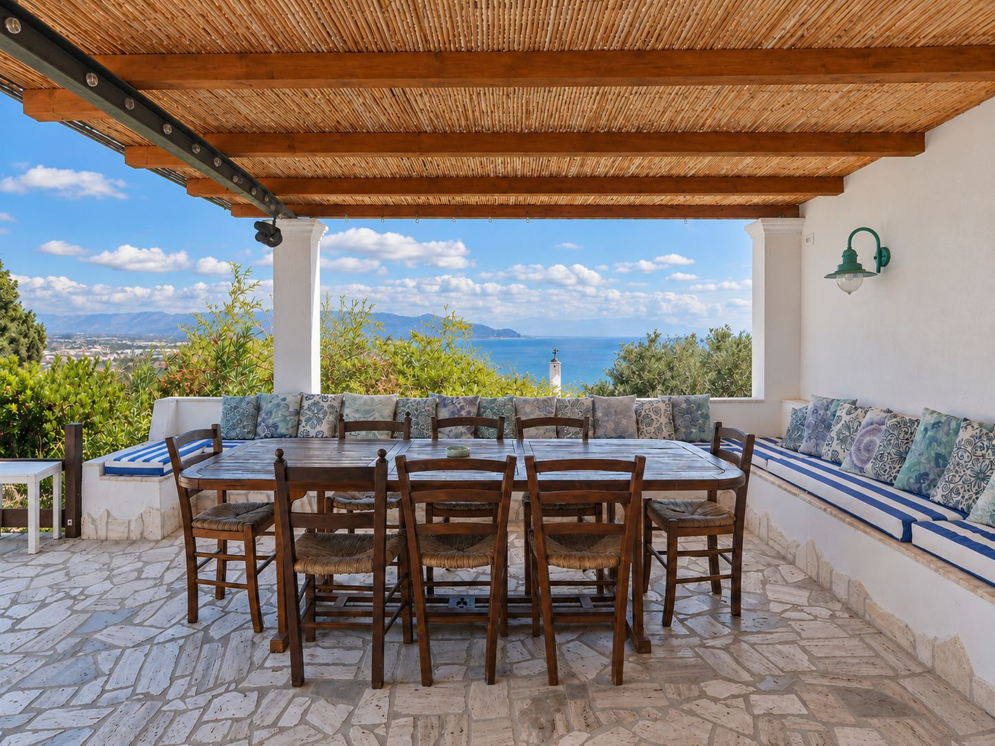 Eine Außenpatio mit Tisch und Stühlen, ein überdachter Bereich mit Meerblick und ein Steinboden.