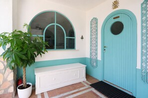 Una puerta turquesa con un ventanal circular y un letrero que dice 'CUISINE'.