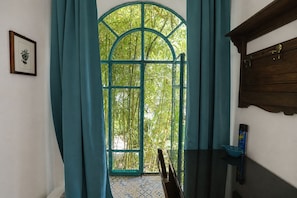 A room with a large arched window, curtains, a wooden cabinet, and a framed botanical print on the wall. - Villa Mariani: Villa in San Felice Circeo (San Felice Circeo)