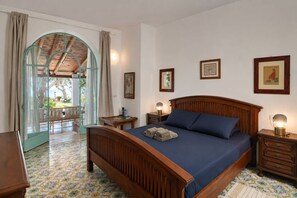 Un dormitorio con cama de madera, una mesita de noche, una lámpara y vistas a un patio exterior.