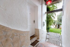 A white door with a brass handle, a stone wall, and a wooden bench outside. - Villa Mariani: Villa in San Felice Circeo (San Felice Circeo)