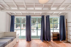 A room with a bed, a wooden bench, and a large window with curtains. - Villa Mariani: Villa in San Felice Circeo (San Felice Circeo)