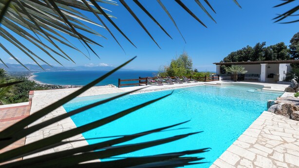 A swimming pool with a view of the sea and mountains.