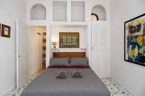Un dormitorio con cama, un cuadro, una lámpara y una puerta.