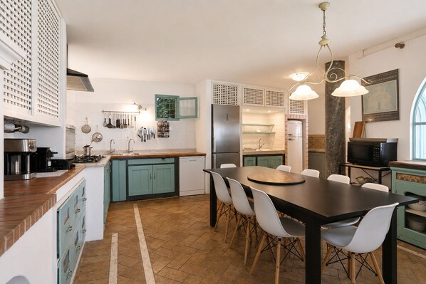 Una cocina moderna con una isla central, armarios blancos y un comedor con una mesa negra y sillas blancas.