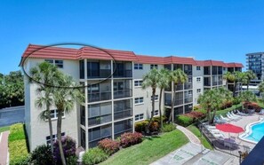 A multi-story hotel with balconies, a swimming pool, and landscaped gardens. - Condo# 414 2 Bed/2 bath Condo Steps to Siesta Key Beach! (Sarasota)