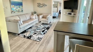 Un salon moderne avec un canapé, une table basse et un téléviseur à écran plat.
