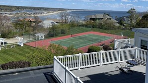 Un court de tennis avec vue sur l’océan et une plage en arrière-plan.