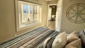 Une chambre à coucher comprenant un lit, un ventilateur de plafond, une fenêtre avec vue et un climatiseur fixé au mur.