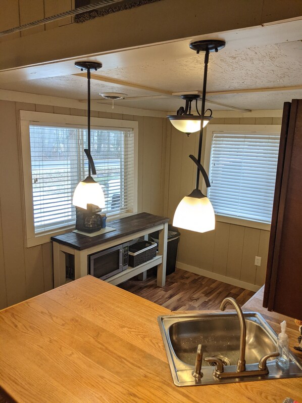 A kitchen with a wooden countertop, a stainless steel sink, and pendant lights.