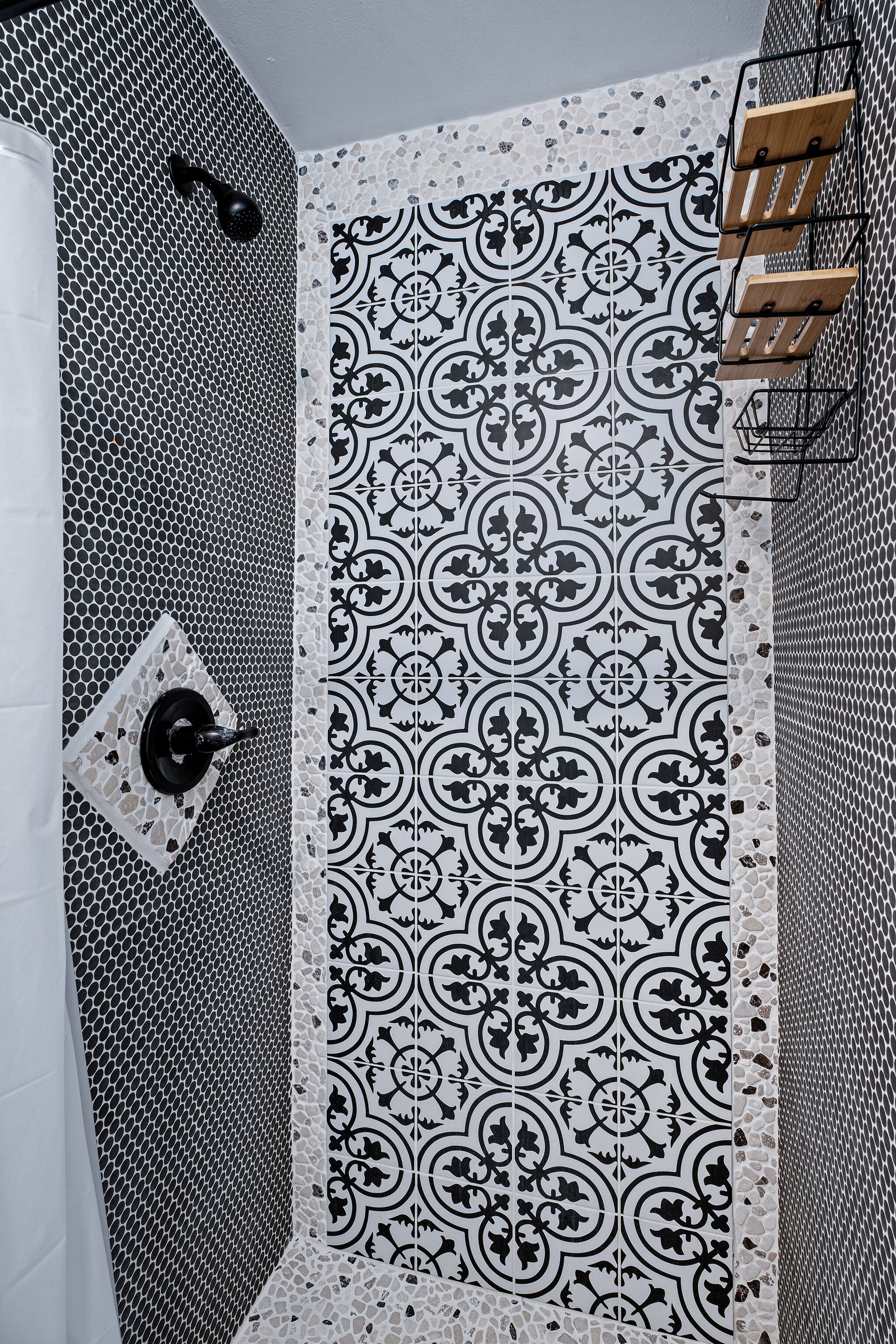 Un baño con un salpicadero de azulejos estampados, zona de ducha y un perchero.