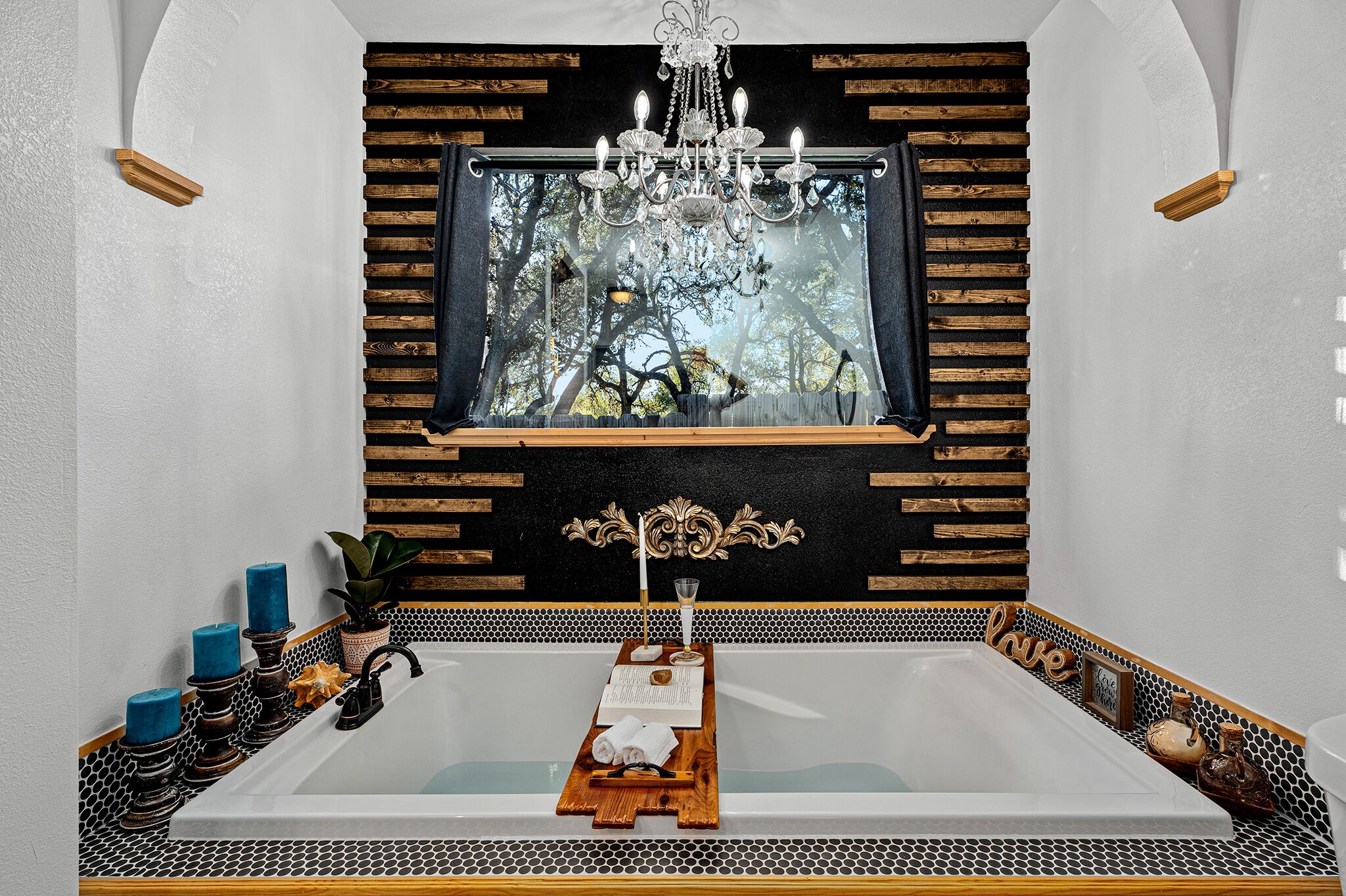 Une salle de bain moderne avec une grande baignoire, un meuble-lavabo en bois et un miroir décoratif placé au-dessus de la baignoire.