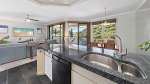 Una cocina moderna con un lavamanos doble, lavavajillas y un comedor con vistas al exterior.