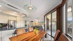 Una cocina moderna con electrodomésticos de acero inoxidable, un comedor con mesa y sillas de madera, y un amplio ventanal corredero que da a un balcón.