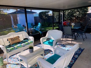 A covered patio with wicker furniture, a view of the backyard, and a dining area with chairs and a table. - Jax Beach 3bd/2bth Single family home/PET friendly16 (Jacksonville Beach)