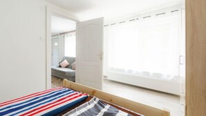 A bedroom with a bed, a window, and a view of a balcony.