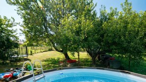 A swimming pool surrounded by trees and a grassy yard.