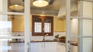 Une cuisine avec des meubles blancs, un plan de travail en bois, un évier et une fenêtre avec un cadre en bois.