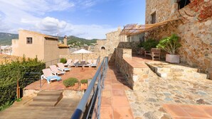 Une terrasse sur le toit, avec des murs en pierre, un petit bâtiment et une vue sur le paysage urbain.