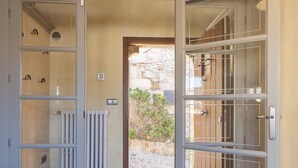 Un couloir avec un radiateur, un mur en pierre et une porte donnant sur l’extérieur.