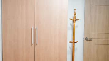 A room with a large wooden wardrobe, a wooden coat stand, and a wooden door.