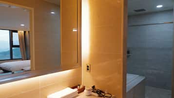 Un bany modern amb un mirall gran, un lavabo amb una pila de tovalloles i una zona de dutxa.
