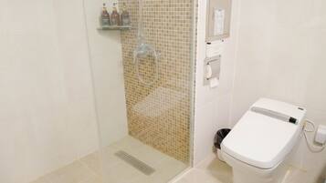 Een badkamer met een douchecabine van glas, een toilet en een plank met toiletartikelen.