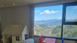 A room with a large window, a playhouse, and two chairs.