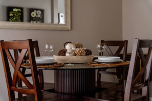 A dining table with four chairs, a central decorative bowl, and two wine glasses. - Comfy and Quiet Retreat, Next to Parks and Trails, Single Level Design, BBQ, 11 Miles to Portland (Beaverton)