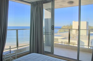 A balcony with a view of the sea and a building across the water. - Ebbtide Unit 37 (Forster)