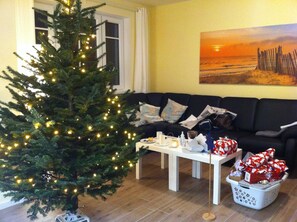 Una sala de estar con un árbol de Navidad, un sofá, una mesa de centro y un cuadro en la pared.